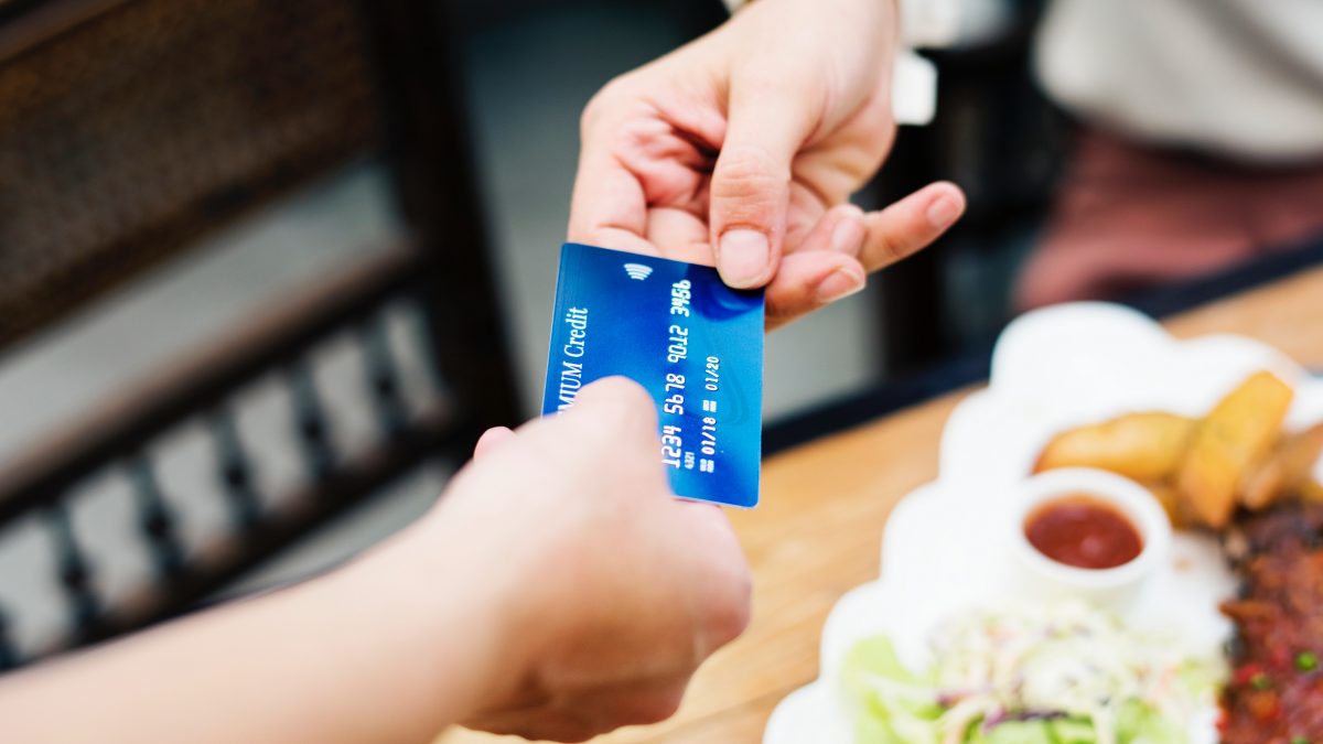 One person handing another credit card in restaurant