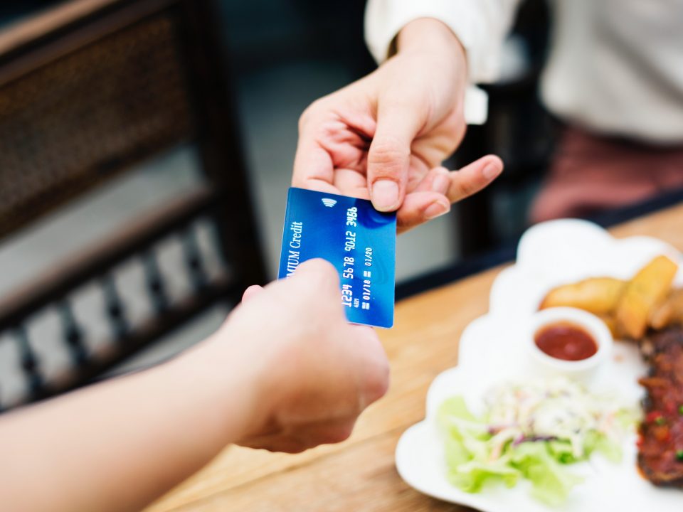 One person handing another credit card in restaurant