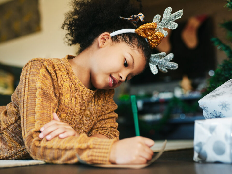 Child, christmas and writing letter, list of wishlist for gift or present from santa claus with hope to celebrate holiday with happiness at home. Girl kid with pencil to write note or xmas card